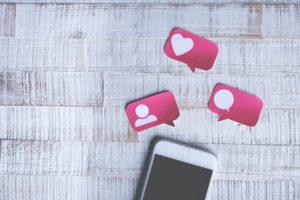 Pink stickies with heart and speech bubbles next to smartphone
