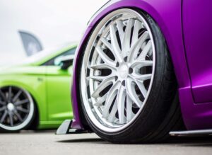 Front wheels of a bright green car and a bright purple car.
